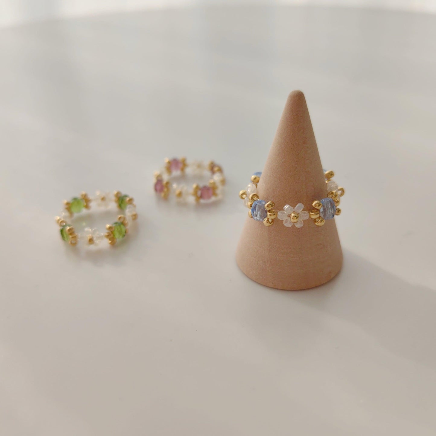 Beaded crystal rings in blue green and purple displayed in a flat lay