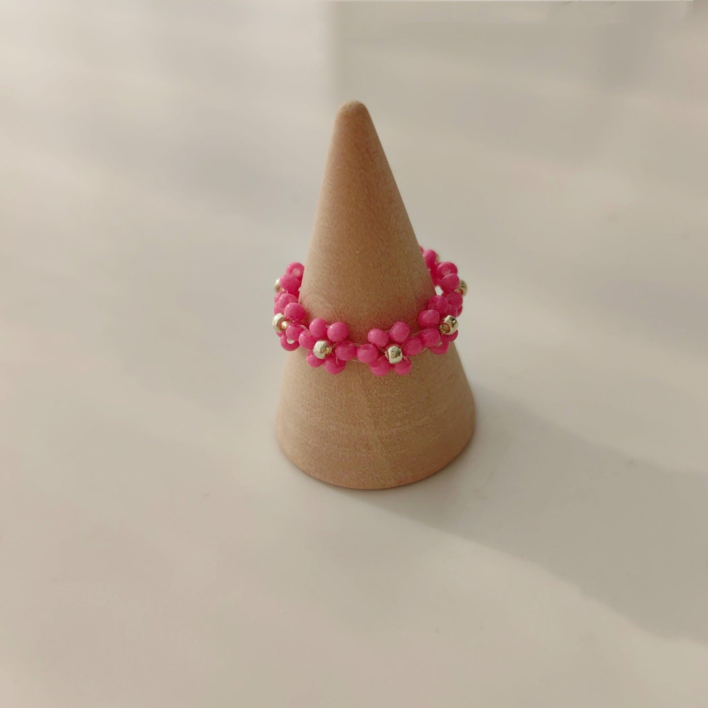 Pink beaded flower ring displayed on a ring stand