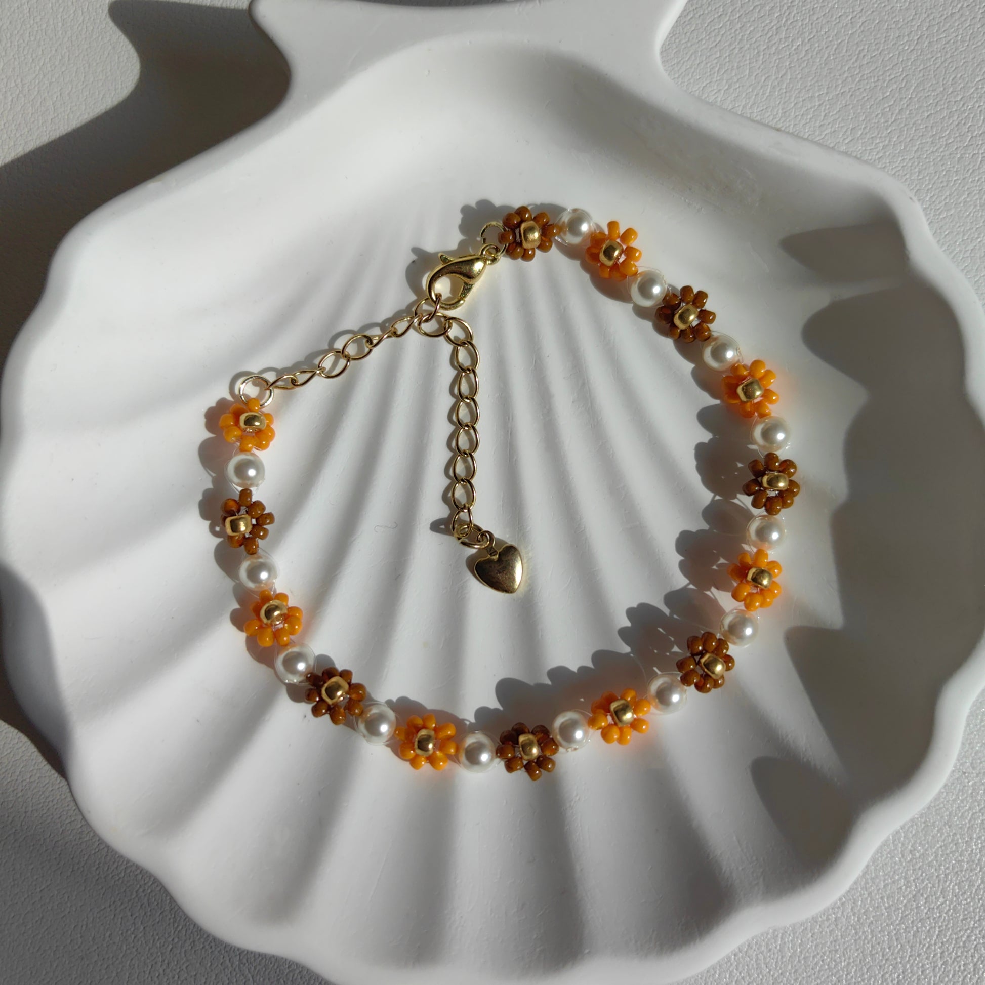 Close-up of autumn seed bead flower bracelet with pearl on a white plate, showing bead details