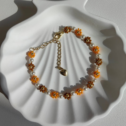 Close-up of autumn seed bead flower bracelet with pearl on a white plate, showing bead details