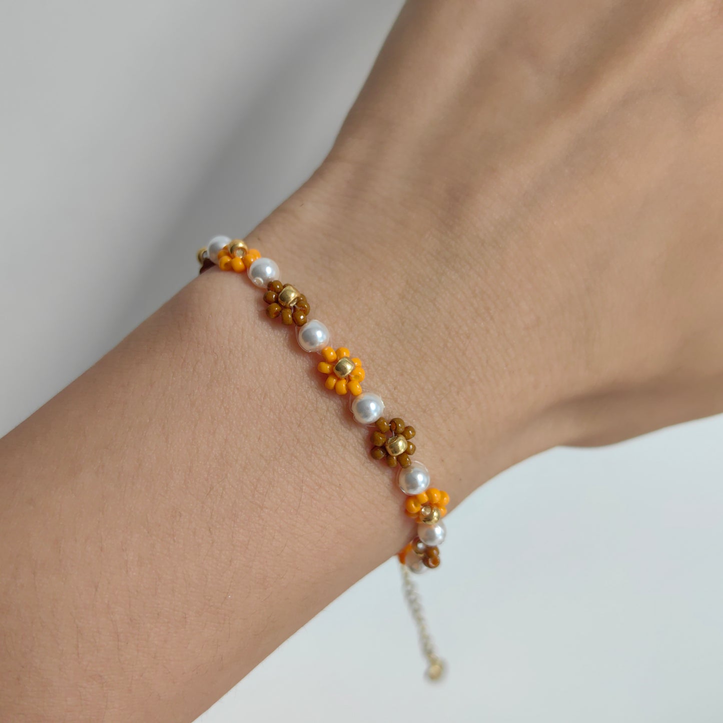Autumn seed bead flower bracelet with pearl worn on wrist, lightweight handmade jewelry