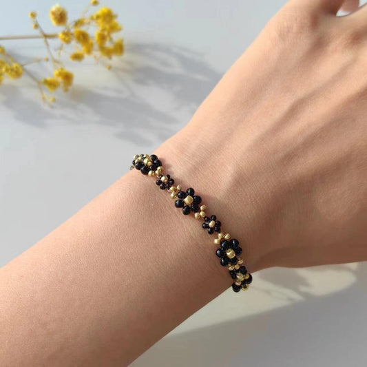 Black Daisy bracelet with black and gold seed beads worn on wrist
