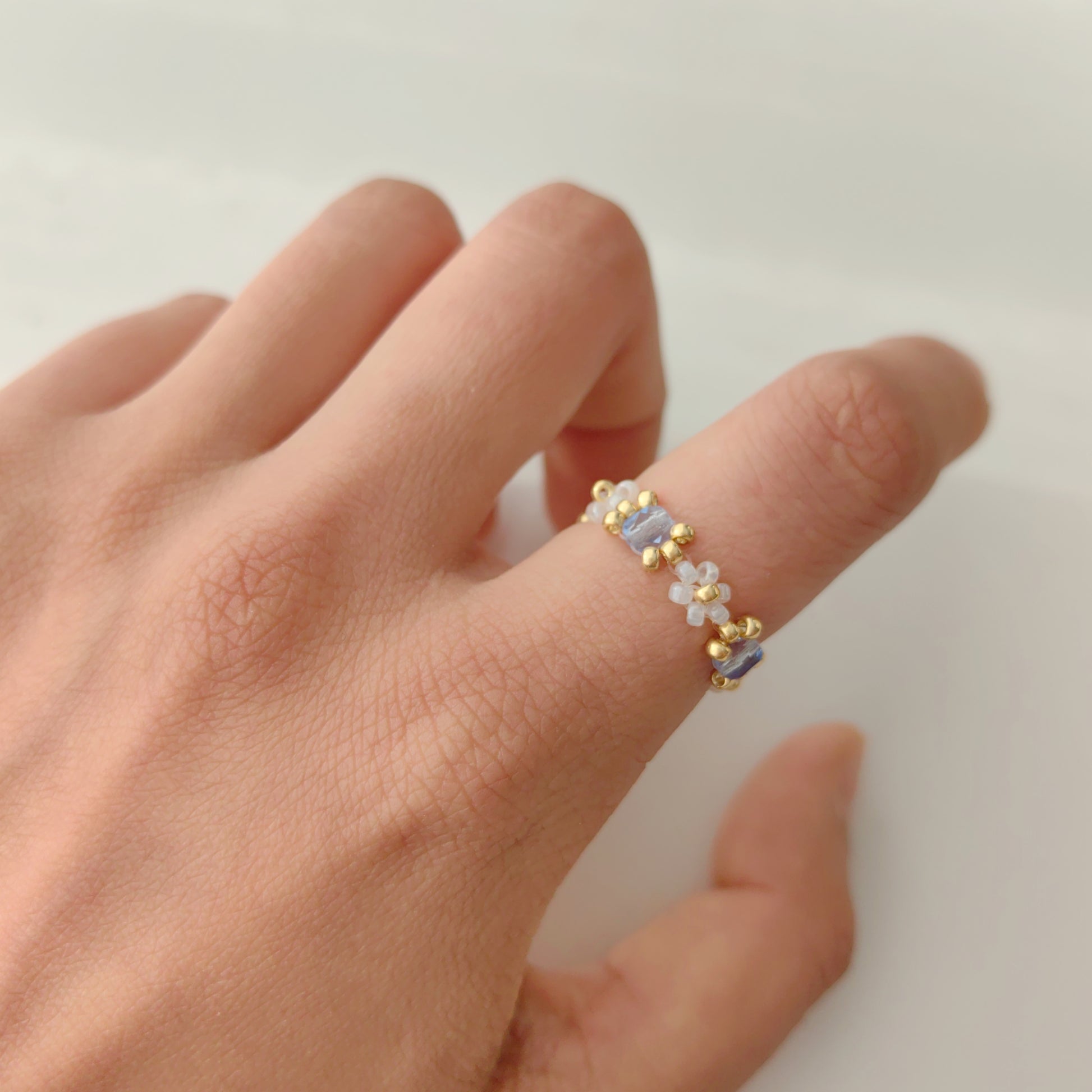 Blue crystal beaded ring made with clear seed beads worn on finger