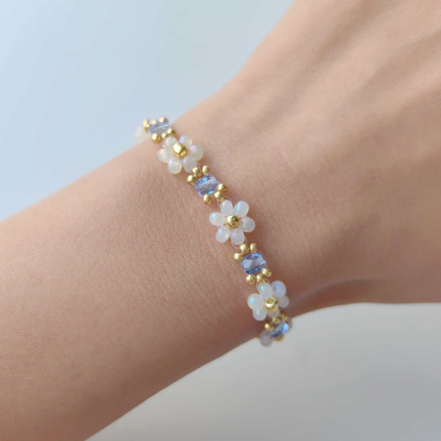 Dainty blue crystal and white seed bead bracelet worn on wrist