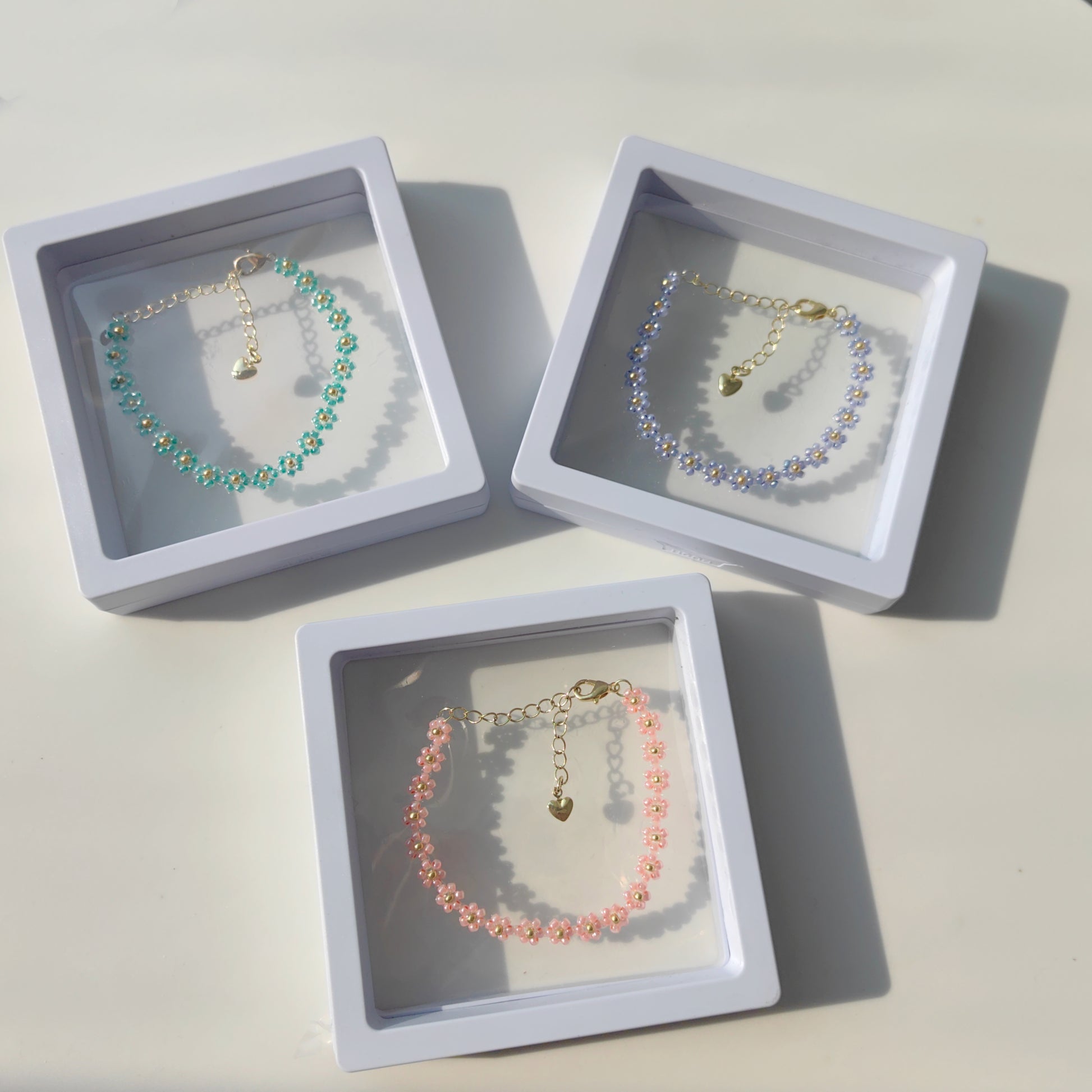 Blue, pink, and green daisy beaded bracelets in jewelry box, colorful handmade seed bead jewelry