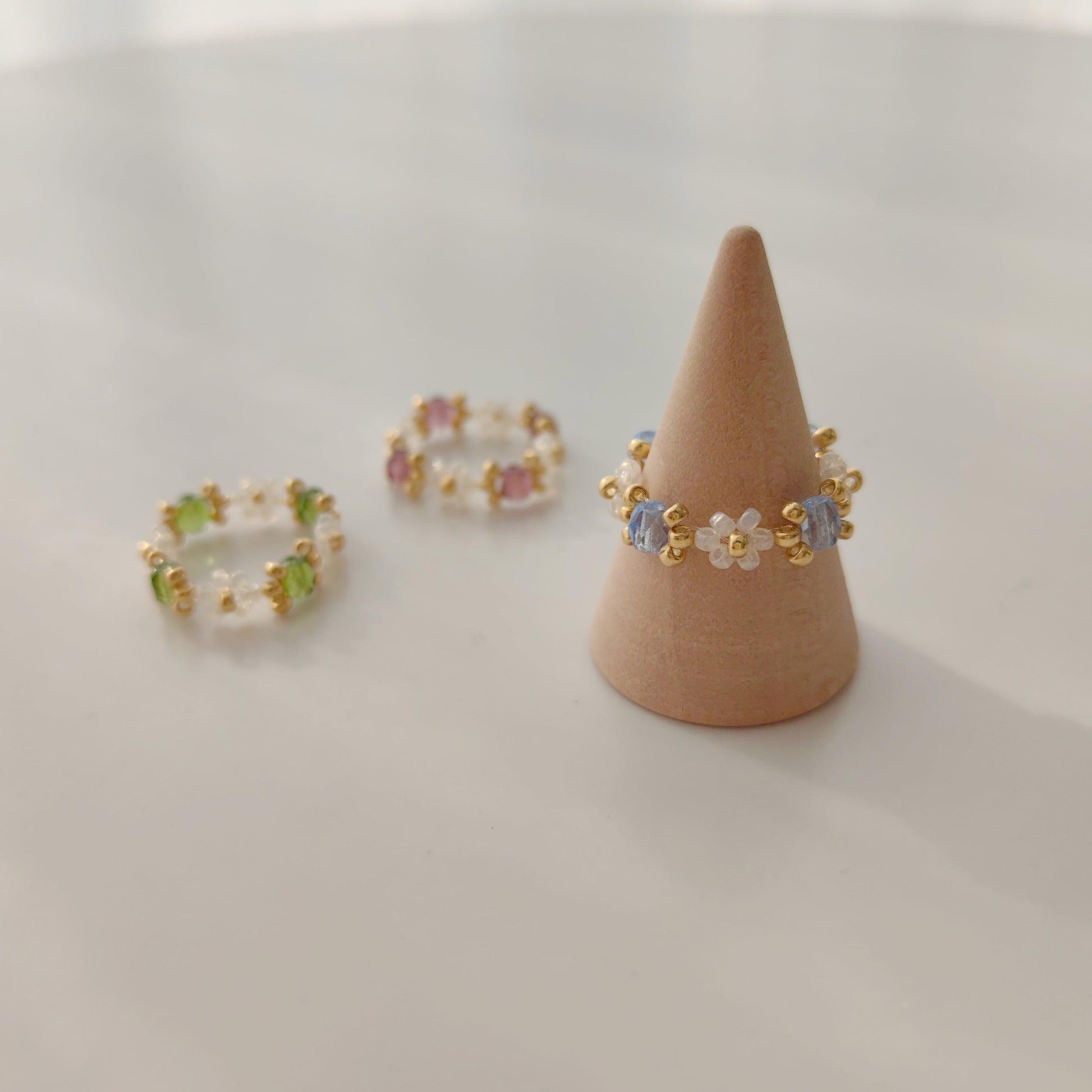 Beaded crystal rings in blue green and purple displayed in a flat lay