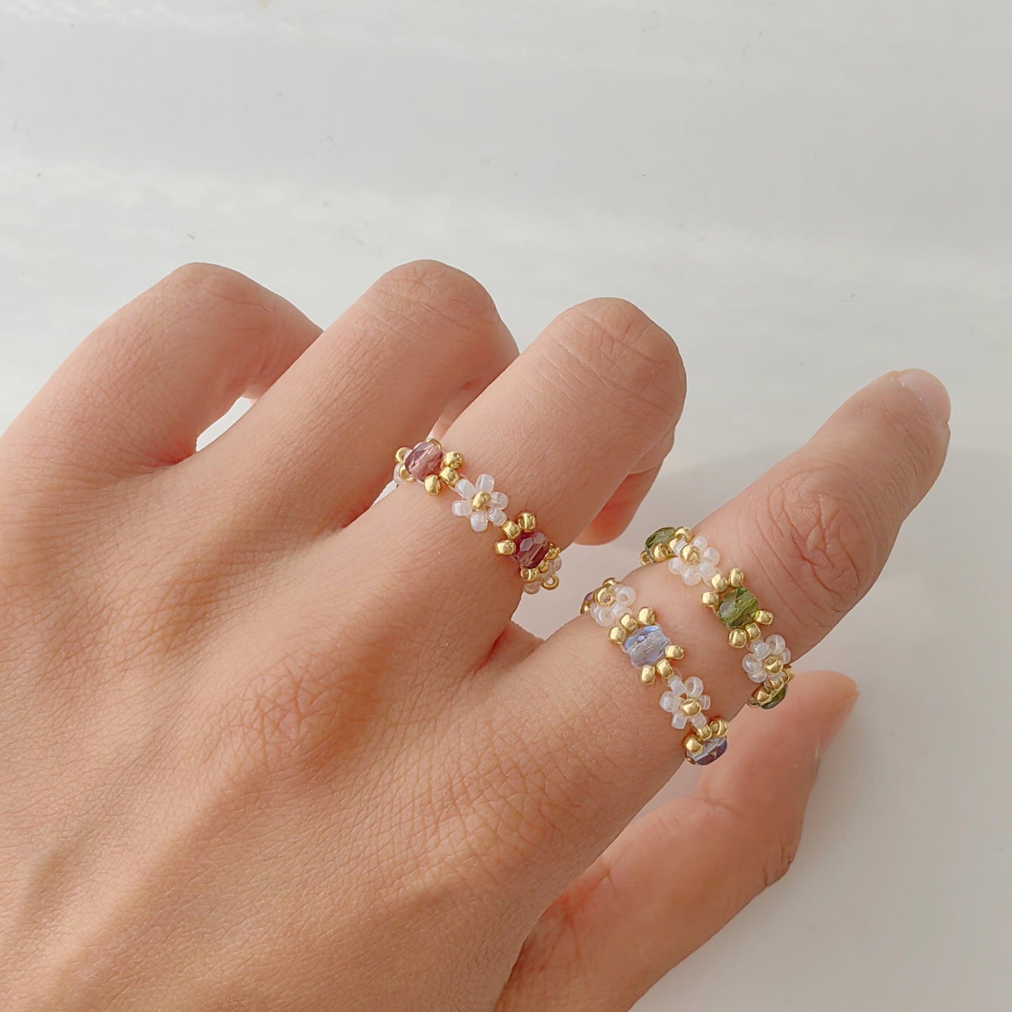Handmade beaded crystal rings in blue green and purple worn on hand