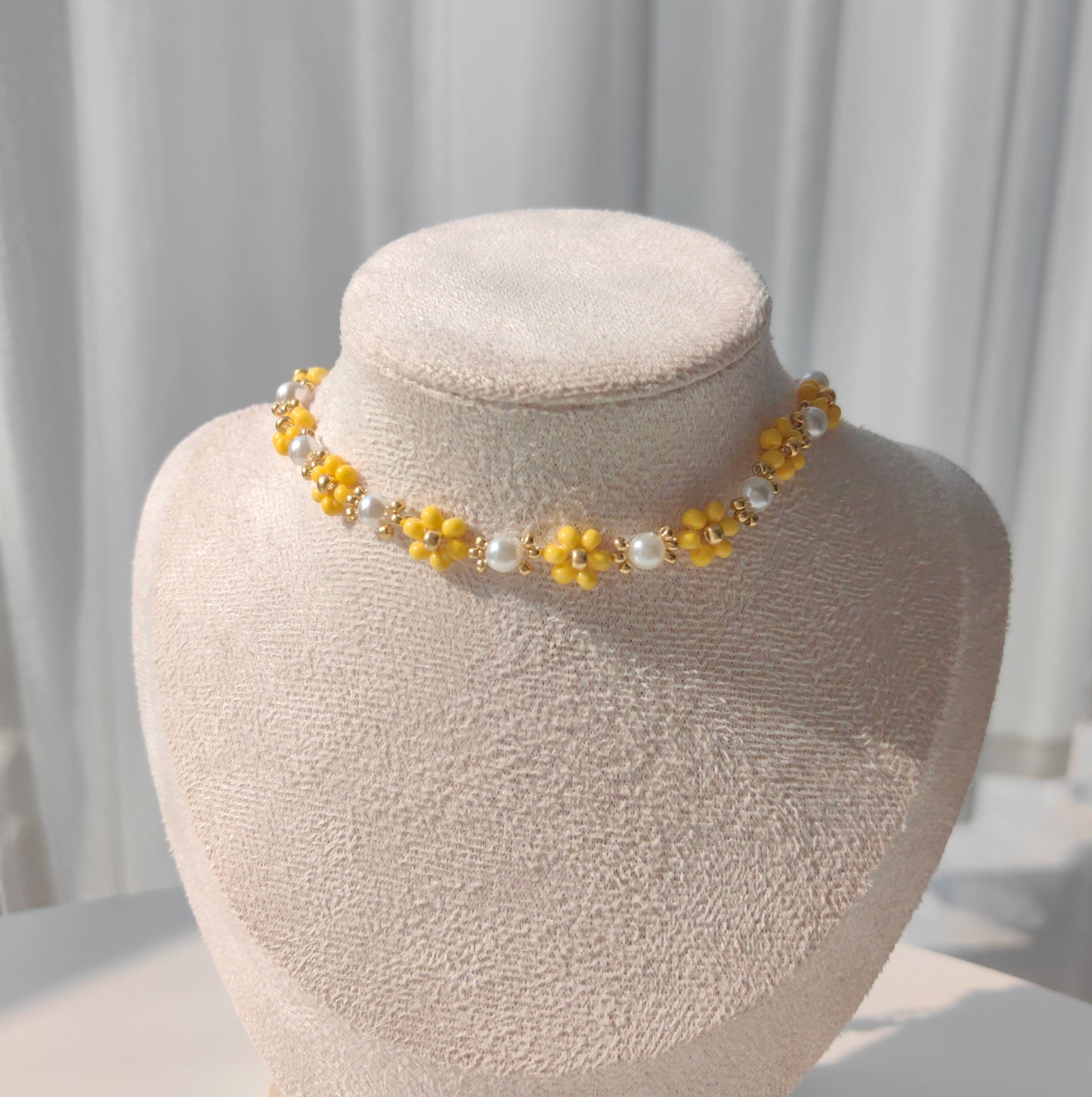 Dandelion Pearl Necklace with yellow beads and pearls on necklace stand