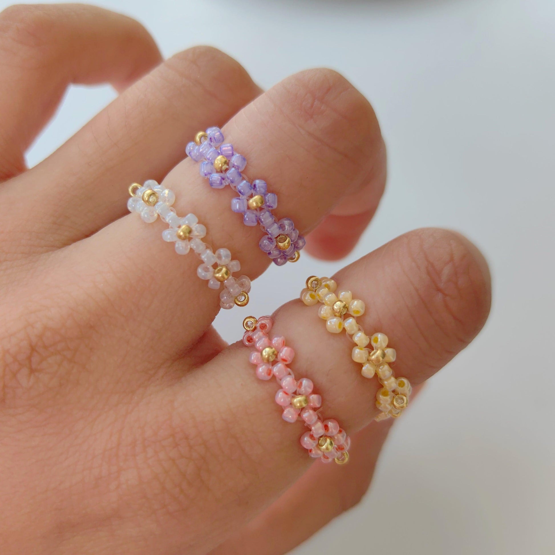Fairytale seed bead rings in pink purple yellow and white worn on hand