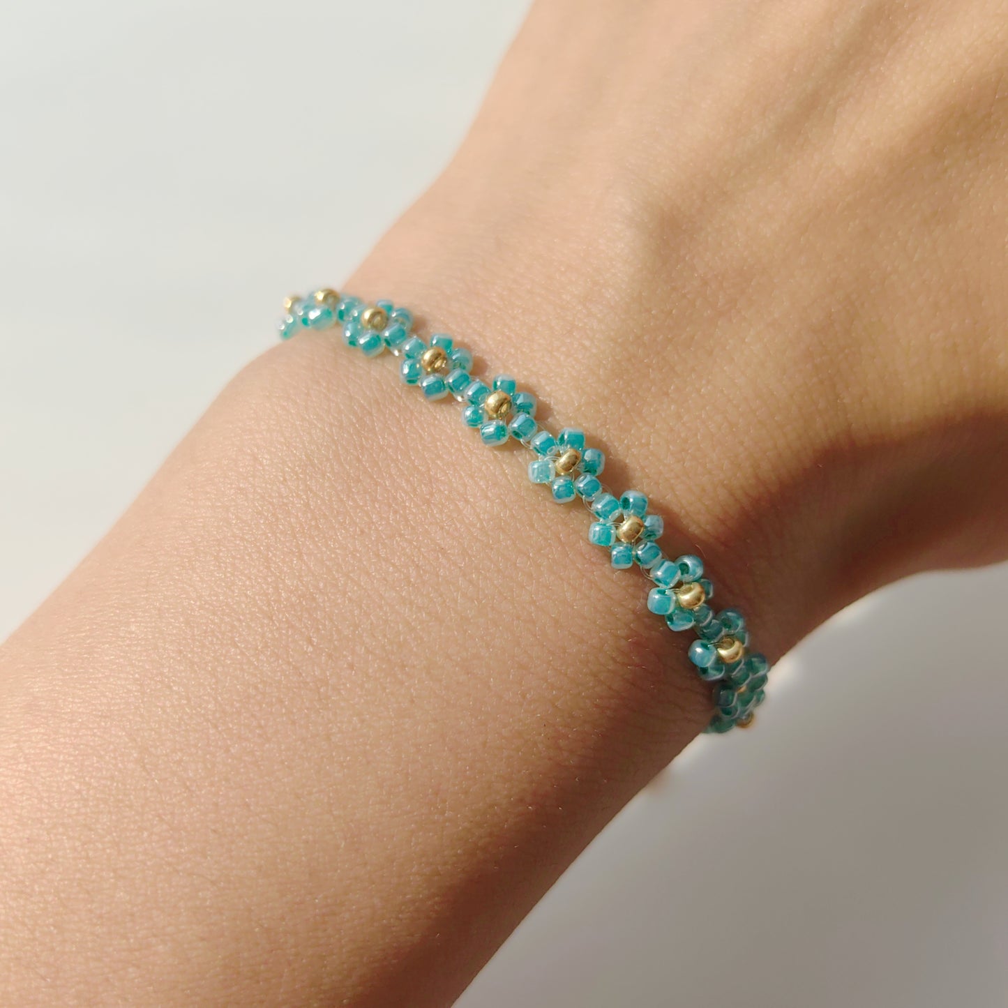 Green daisy beaded bracelet worn on wrist, delicate handmade flower seed bead bracelet