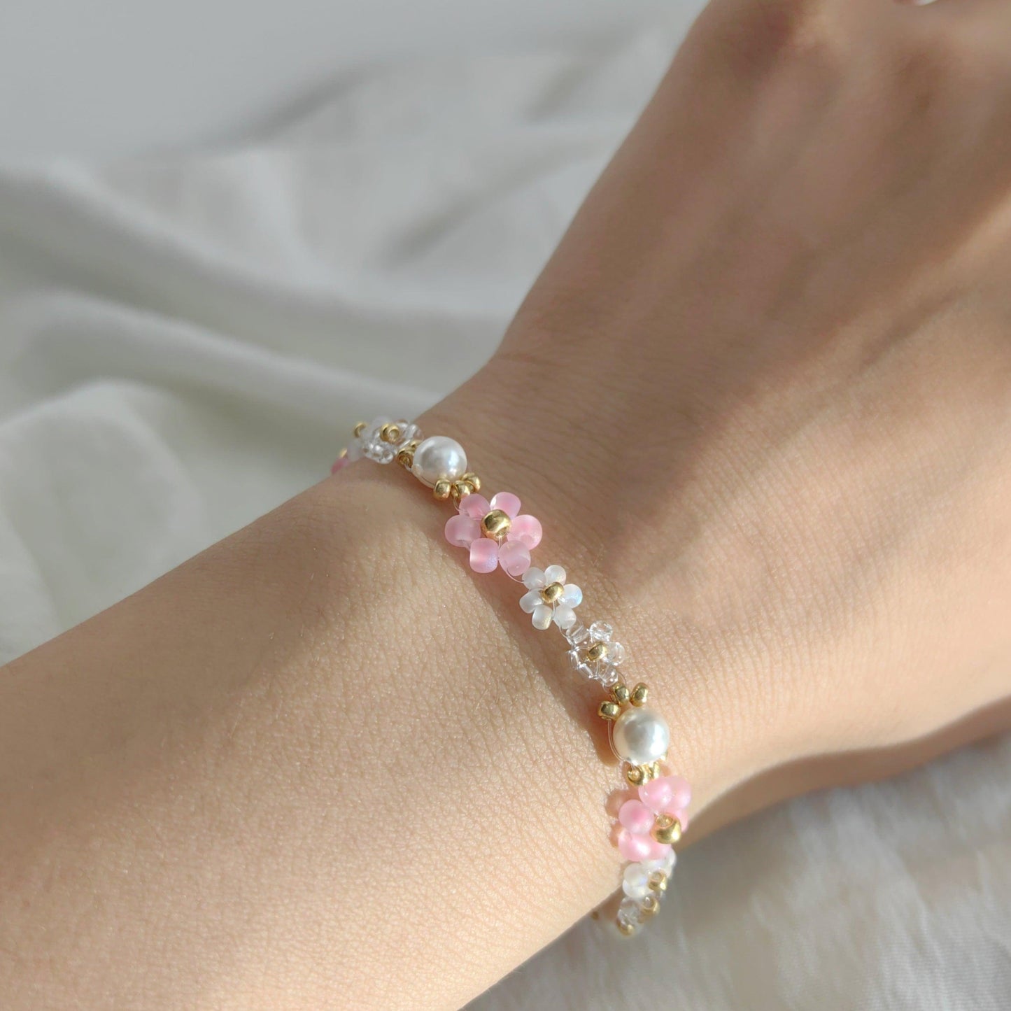 Handmade pink and white beaded bracelet with pearl worn on wrist