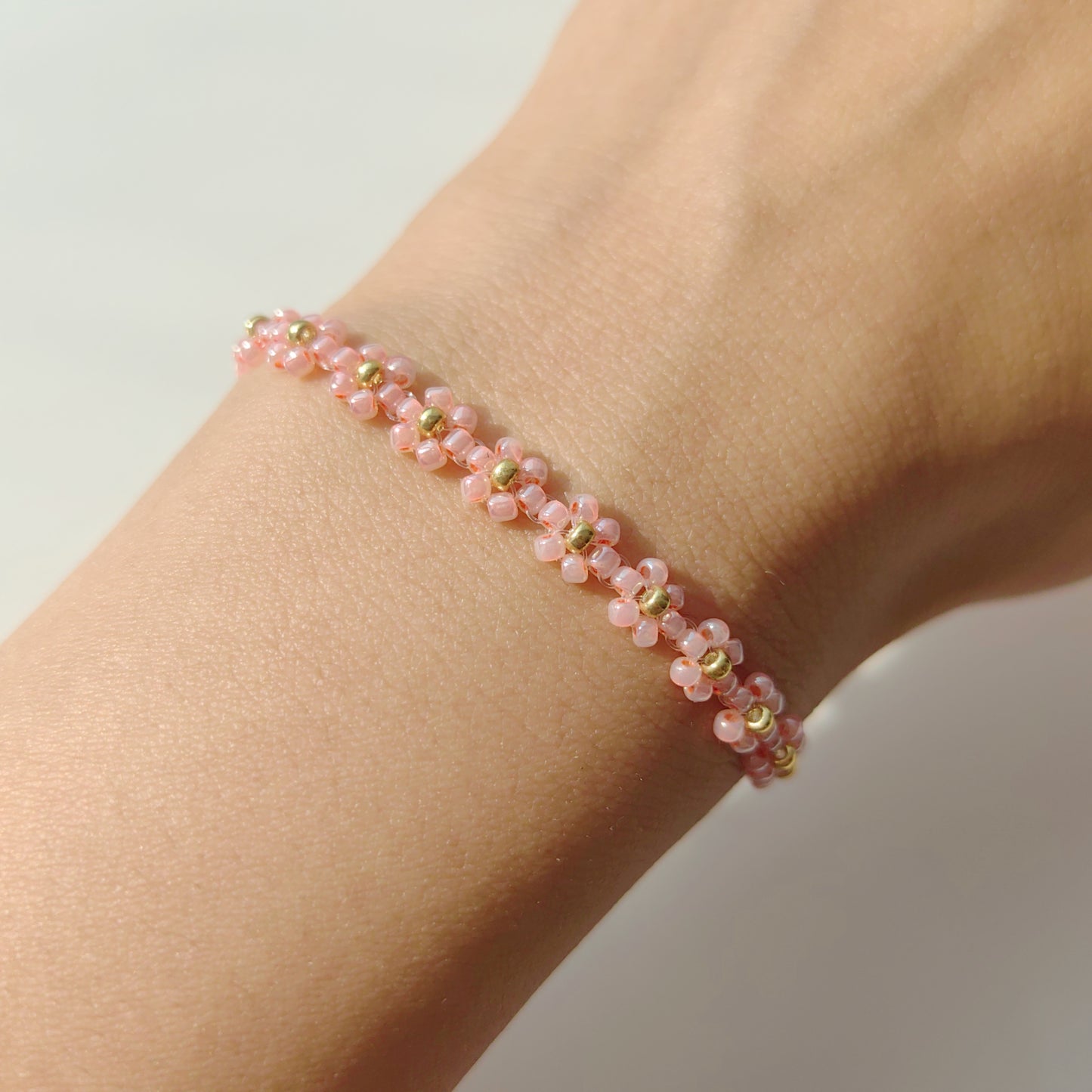 Pink daisy beaded bracelet worn on wrist, cute handmade floral seed bead bracelet
