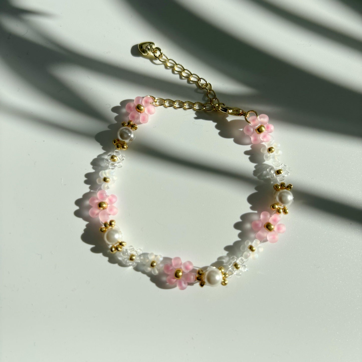 Pink and white beaded bracelet with  pearls on a  white background