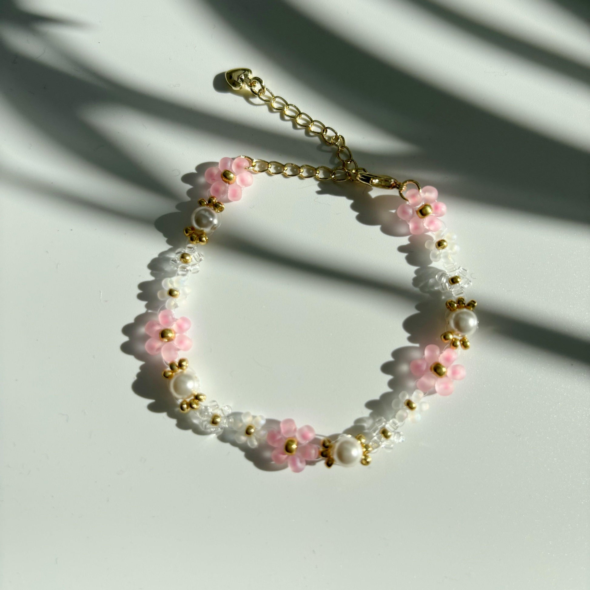 Pink and white beaded bracelet with  pearls on a  white background