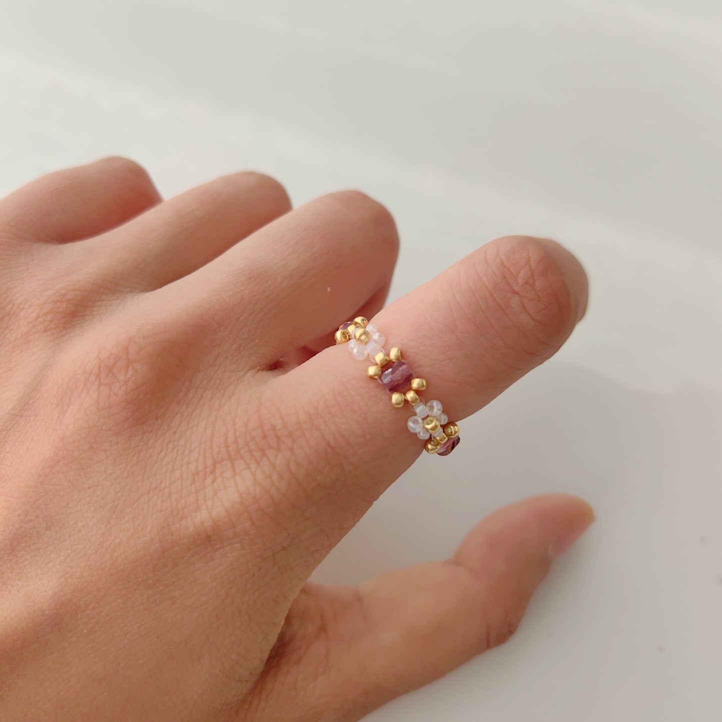 Purple crystal beaded ring with clear seed beads worn on finger