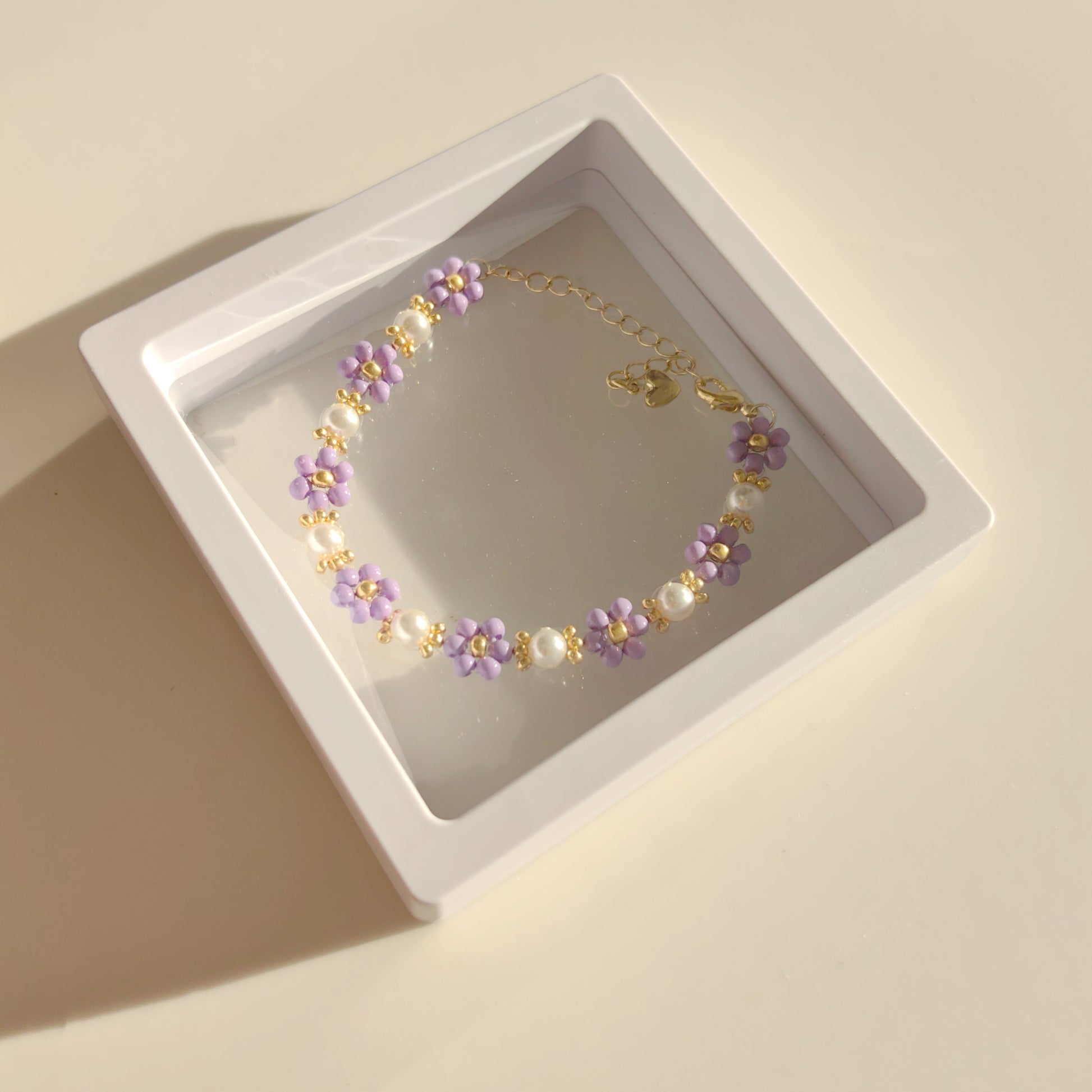 Purple seed bead bracelet and pearl worn with package