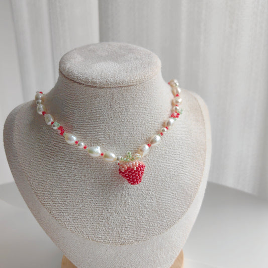 Handmade strawberry bead necklace displayed on a jewelry stand