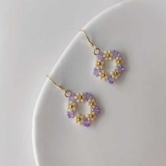 White purple and gold beaded hoop earrings displayed on  white background